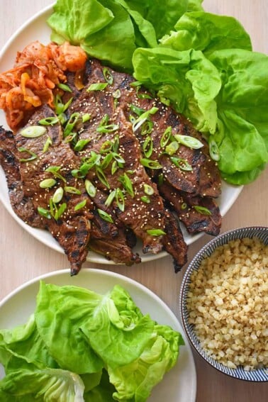 An overhead shot of paleo and Whole30 kalbi (Korean BBQ short ribs) served with Cauliflower rice, kimchi, and butter lettuce leaves.