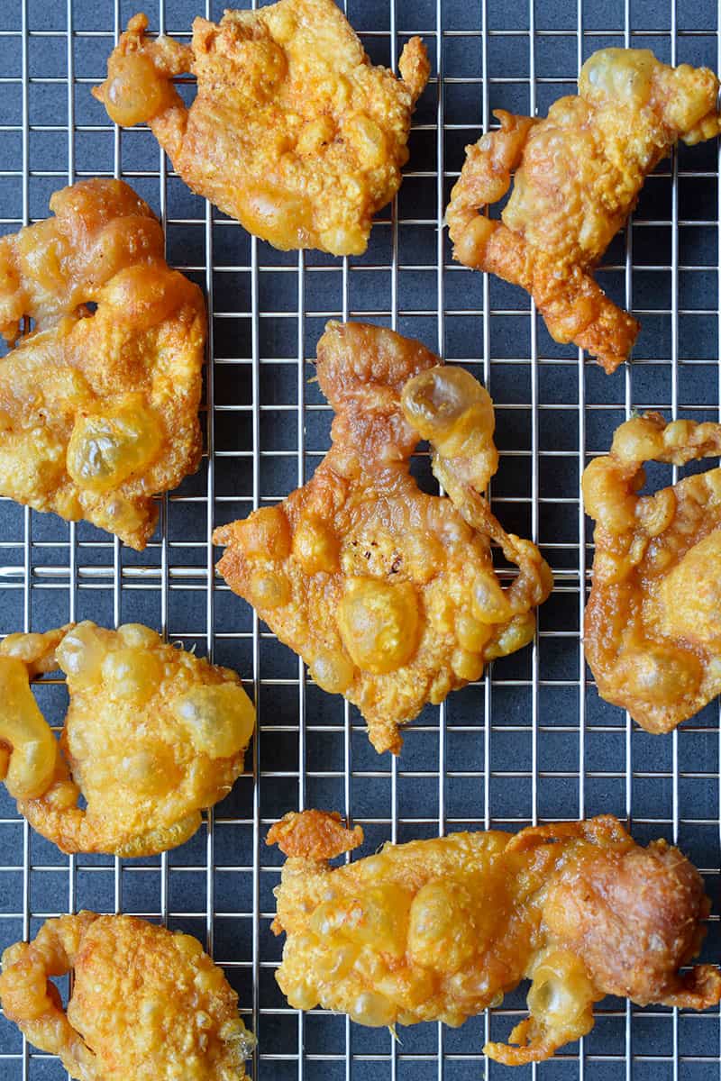 An overhead shot of golden brown chicken cracklings cooling on a wire rack, the perfect paleo, Whole30, keto, and low carb snack.