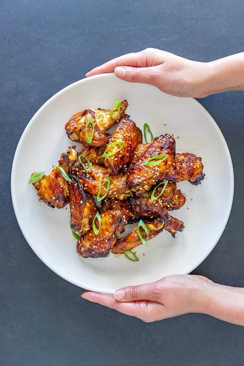 Two hands holding a platter of Whole30 and Paleo easy Chinese Chicken Wings