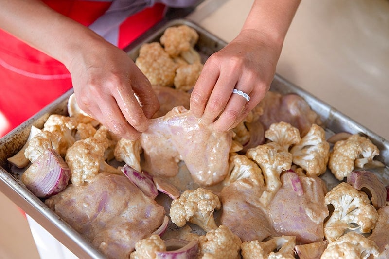 Arranging chicken thighs in a single layer on a baking tray.