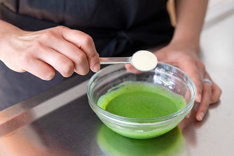 Adding a spoonful of gelatin to the coconut milk and matcha mixture for paleo matcha pudding.