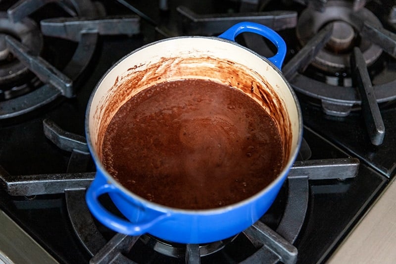 Closeup of the dairy-free chocolate pudding in a blue sauce pan after it has simmered and taken off the heat.