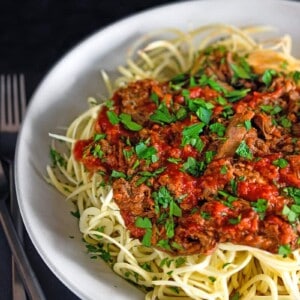 A large white bowl filled with spiralized sweet potato noodles topped with Whole30 Instant Pot Meat Sauce, an easy and healthy dinner.