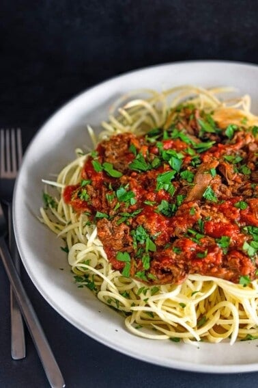 A large white bowl filled with spiralized sweet potato noodles topped with Whole30 Instant Pot Meat Sauce, an easy and healthy dinner.