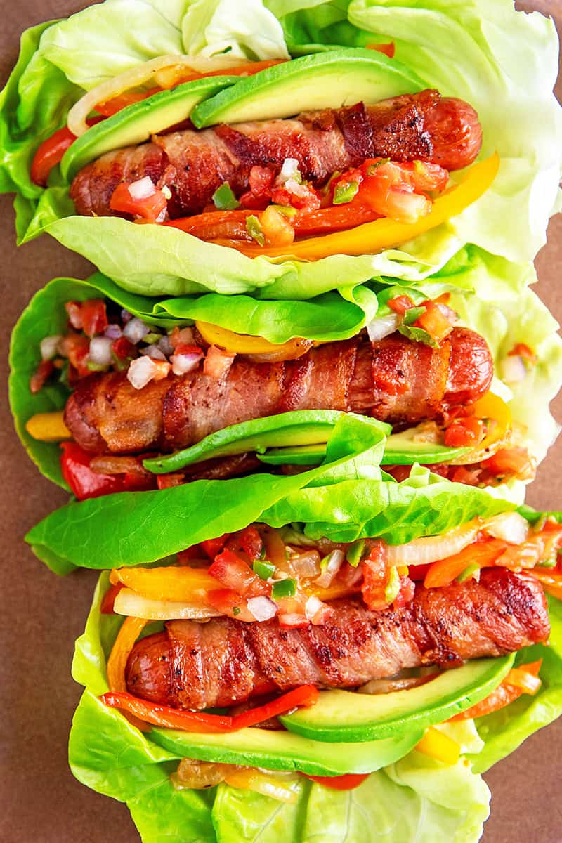 An overhead shot of Whole30, keto, and paleo Sonoran hot dogs wrapped in lettuce and topped with salsa.