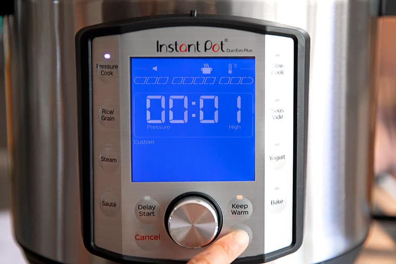 An Instant Pot display showing "00:01" and the pressure cook button lit up.