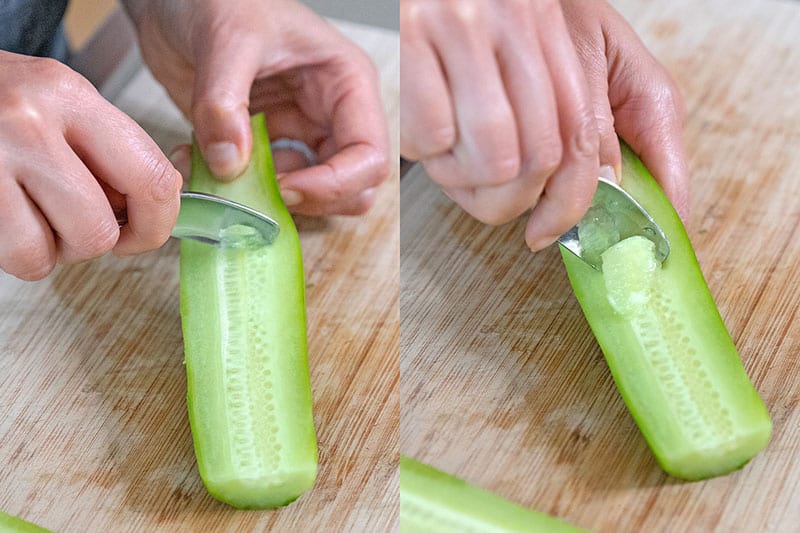 Using a metal teaspoon to scoop out the seeds from a peeled Persian cucumber.