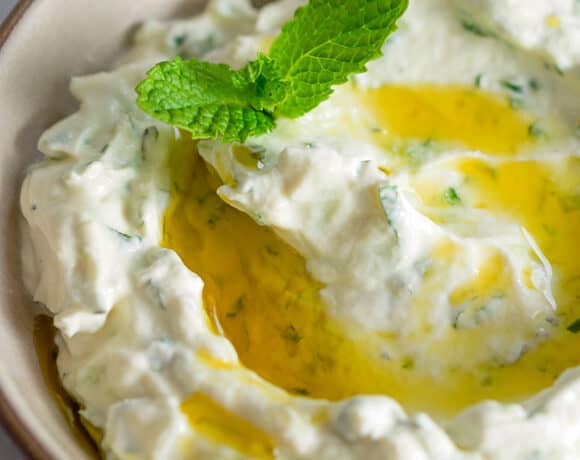 An overhead shot of keto, low carb, paleo, and Whole30 Tzatziki Sauce in a brown bowl topped with olive oil and mint.