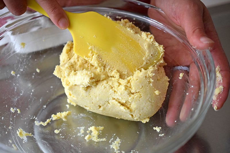 A silicone spatula is folding in cold water into the nut-free and gluten-free galette dough.