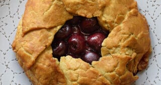 An overhead shot of paleo and gluten-free cherry galette on a white plate