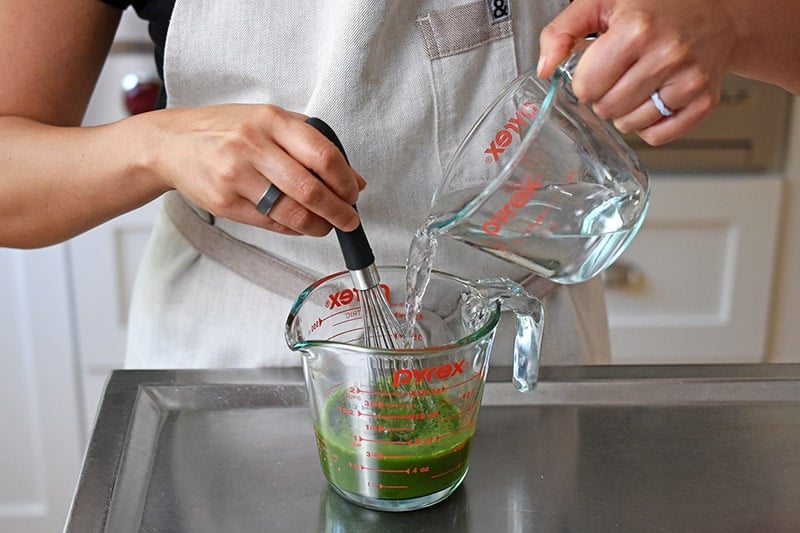 Pouring water into the matcha mixture in the liquid measuring cup.