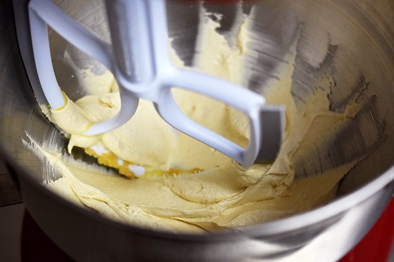 The creamed ghee and maple sugar is now a pale yellow color in the inside of a bowl of a stand mixer.
