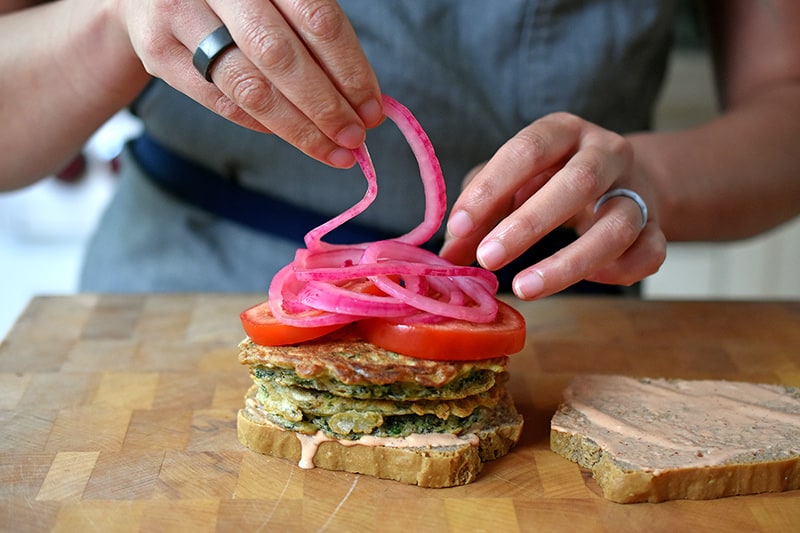 Adding quick pickled onions on a paleo and gluten-free St. Paul sandwich.