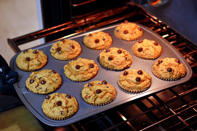 Rotating a tray of gluten free pumpkin chocolate chip muffins in the oven at the halfway cooking point.