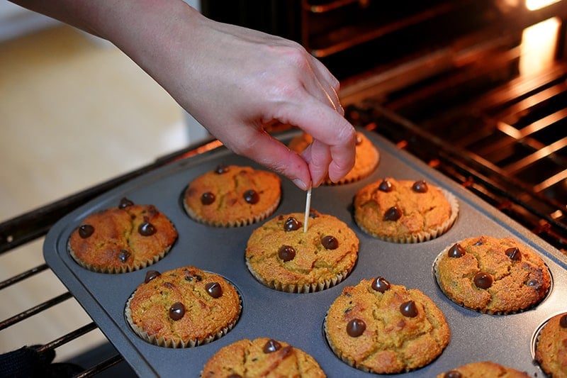 Checking if the grain free pumpkin chocolate chip muffin are ready with a toothpick inserted into the middle of one.