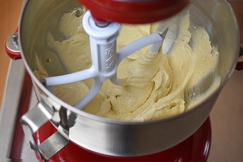 An overhead shot of ghee and maple sugar creamed together in a stand mixer. The batter is light yellow and creamy.