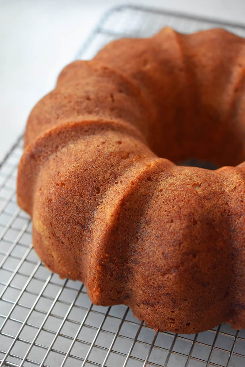 An apple Bundt Cake cooling on a cooling rack after the bundt pan has been removed.