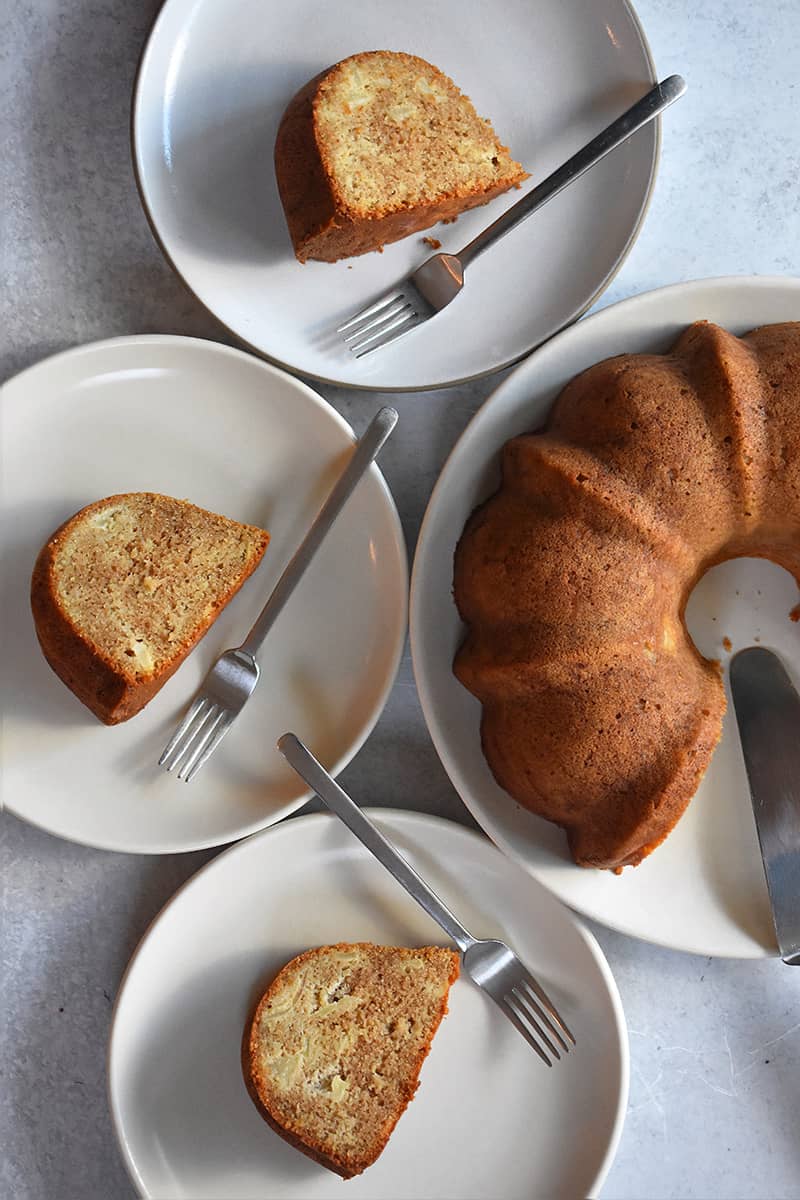 An overhead shot of paleo and gluten free apple Bundt Cake surrounded by three plates with cake slices