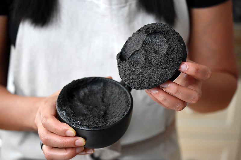 Someone revealing the interior of a black sesame mug cake.