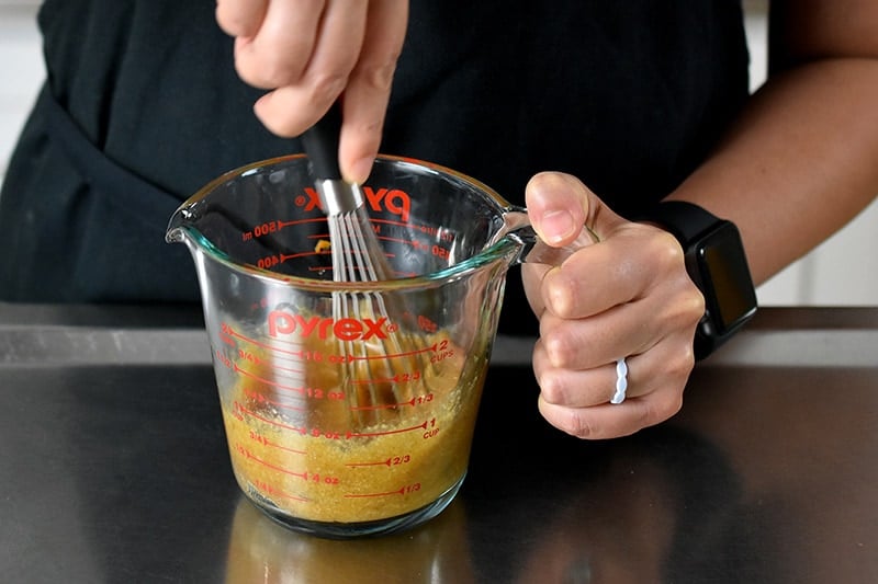 Someone whisking the pumpkin mug cake batter in a liquid measuring cup.