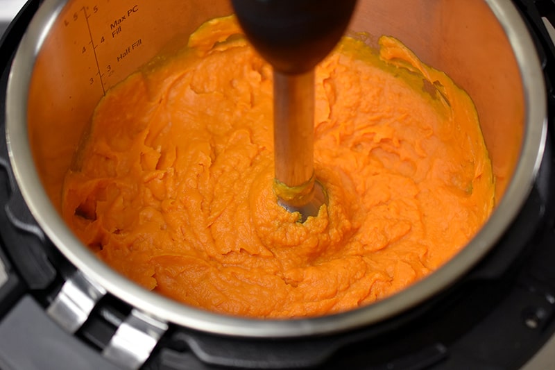 An overhead shot of an immersion blender blending together instant pot mashed sweet potatoes