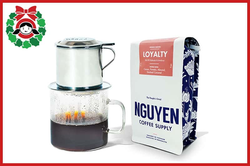 A Vietnamese Coffee Filter over a clear glass mug and a bag of Nguyen Coffee supply coffee, a recommendation on the Nom Nom Paleo 2020 holiday gift guide.