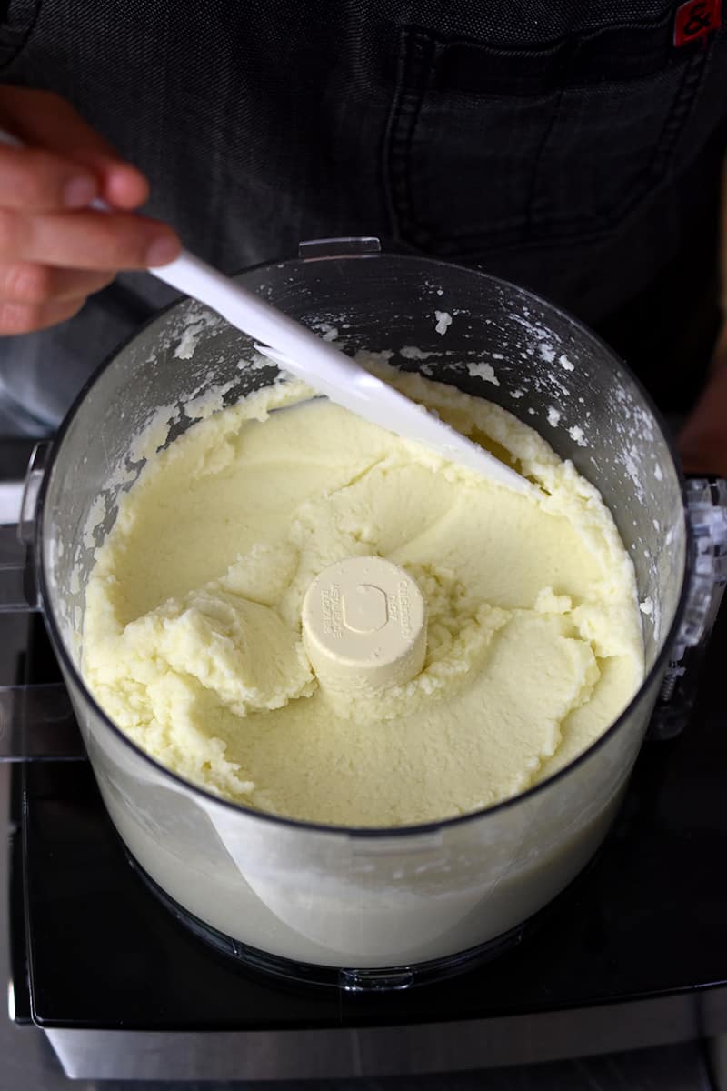 An overhead shot of an open food processor filled with smooth, pureed cauliflower.