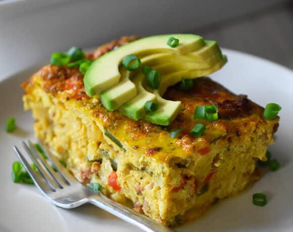A slice of Mexican Breakfast casserole is on a plate in front of a casserole pan.