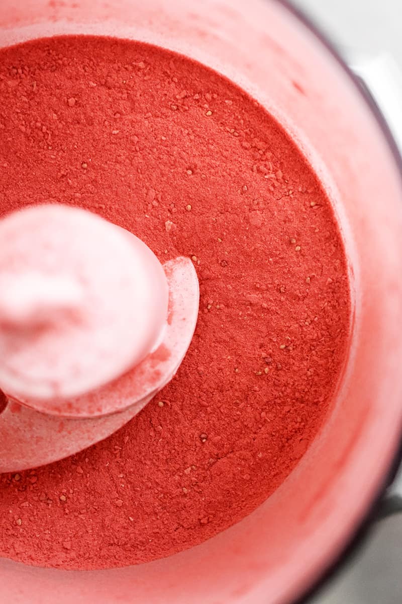 An overhead shot of an open food processor with powdered freeze dried strawberries inside.