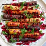 An overhead shot of grilled carrots with herby coconut yogurt and spicy beet vinaigrette.