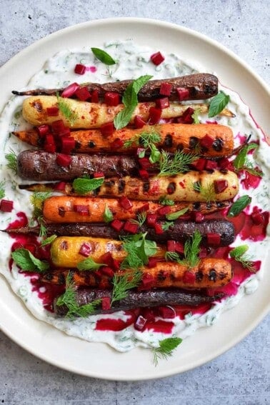 An overhead shot of grilled carrots with herby coconut yogurt and spicy beet vinaigrette.