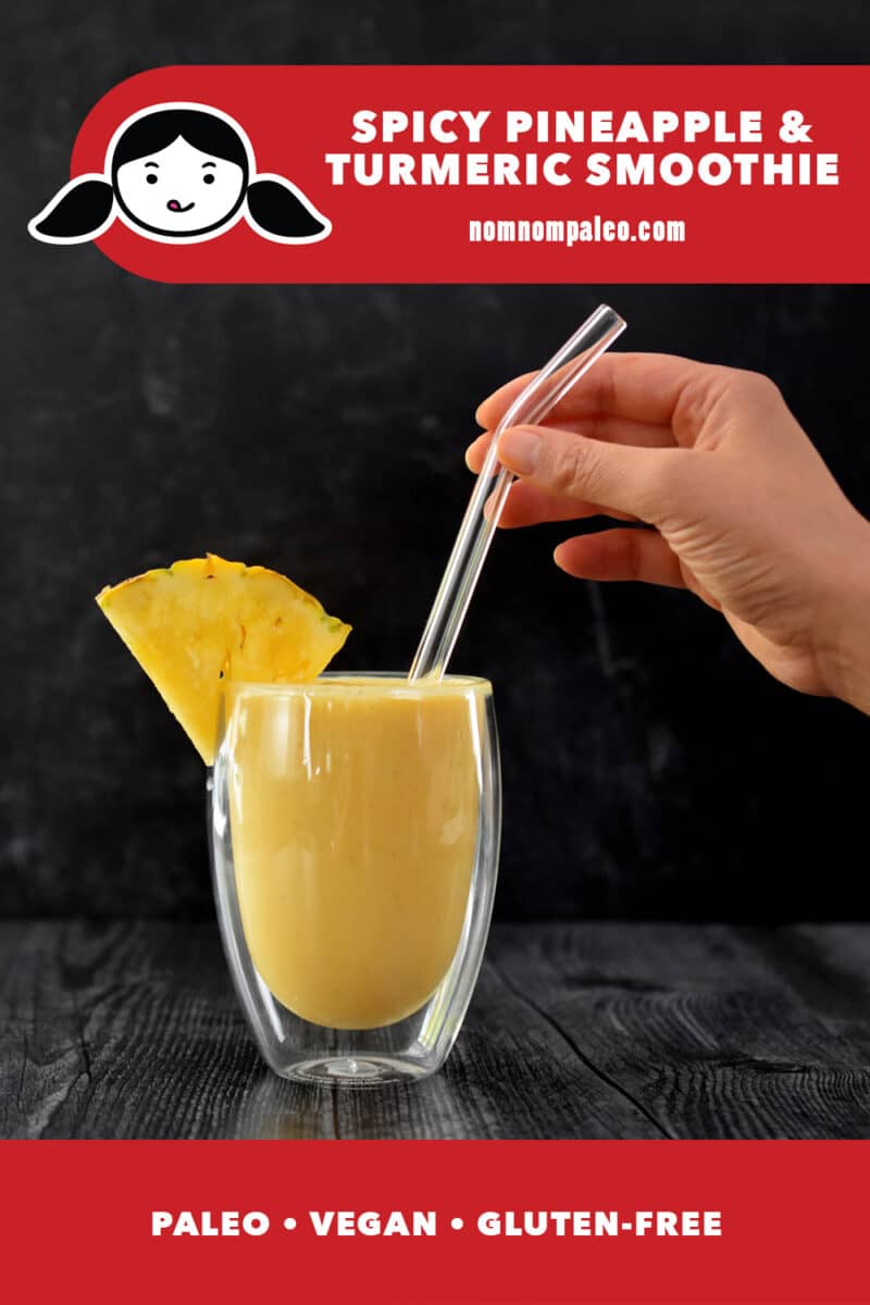 A hand is holding a glass straw that is in a clear glass filled with spicy pineapple turmeric smoothie. The red banner at the bottom says paleo, vegan, gluten-free