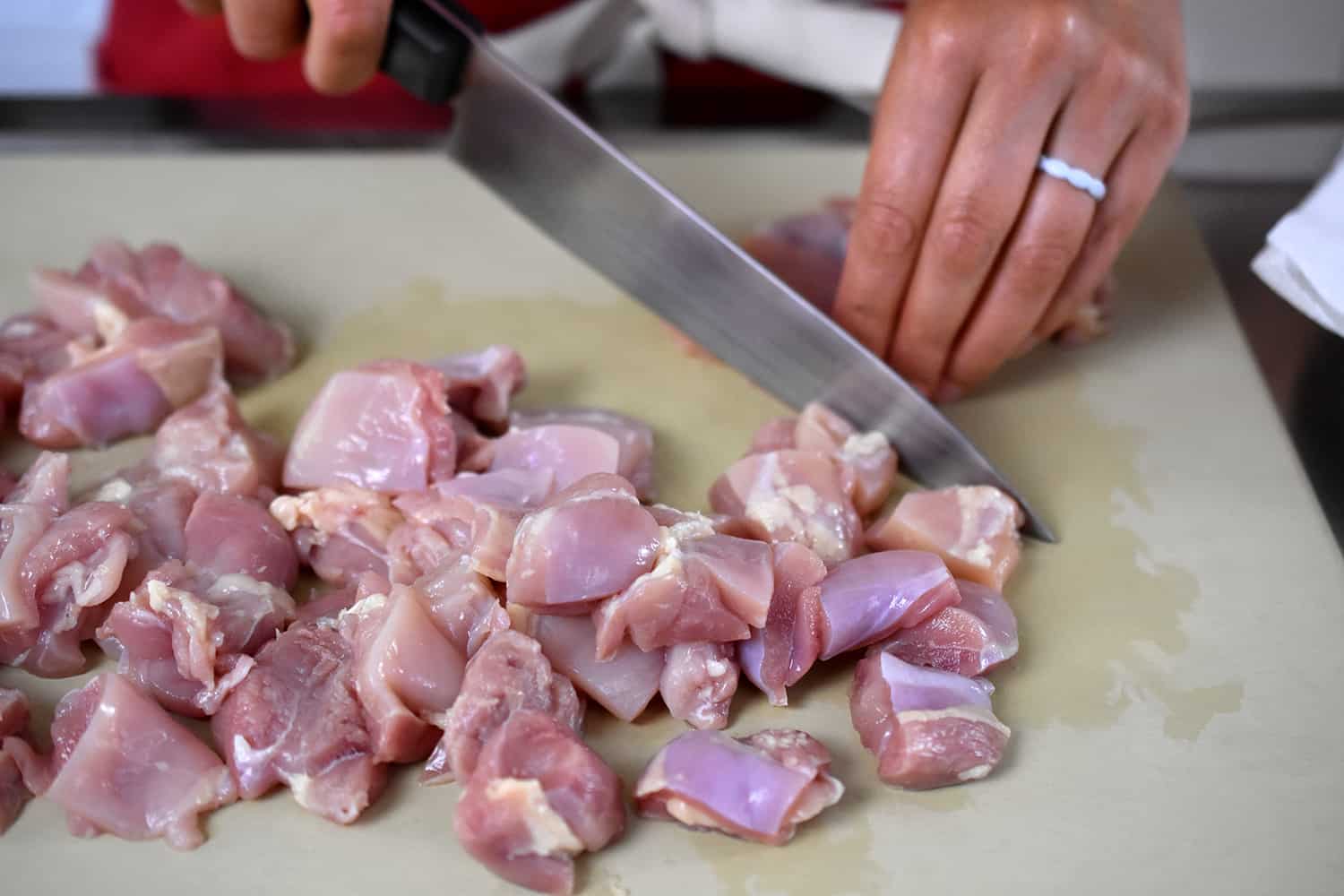 Cutting boneless skinless chicken thighs into bite-sized pieces