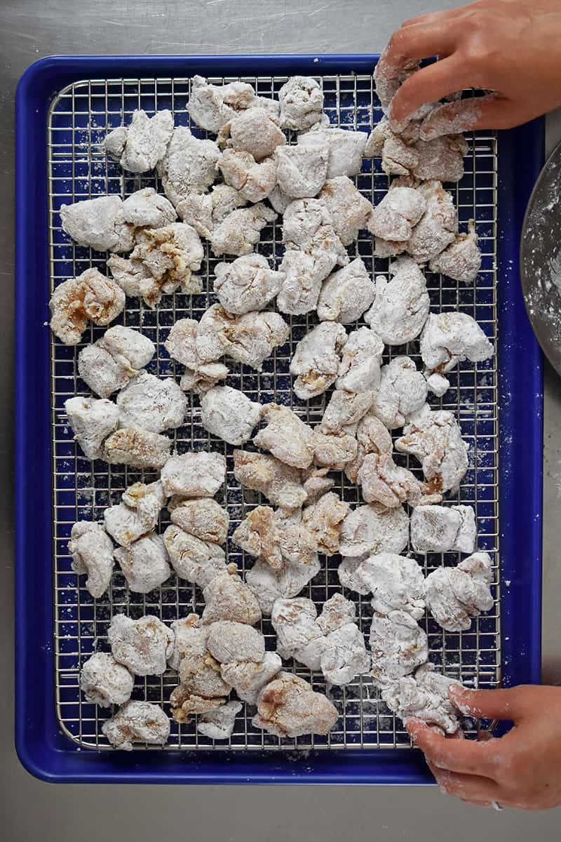 An overhead shot of battered Taiwanese Popcorn chicken on a wire rack in a rimmed baking sheet.