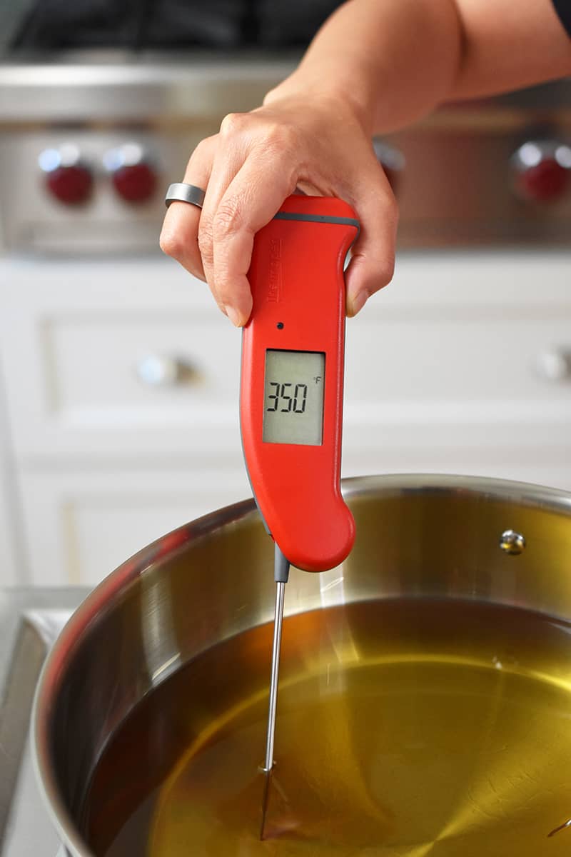 An instant read thermometer shows that the oil in a pot is 350°F, the ideal temperature for deep frying chicken.