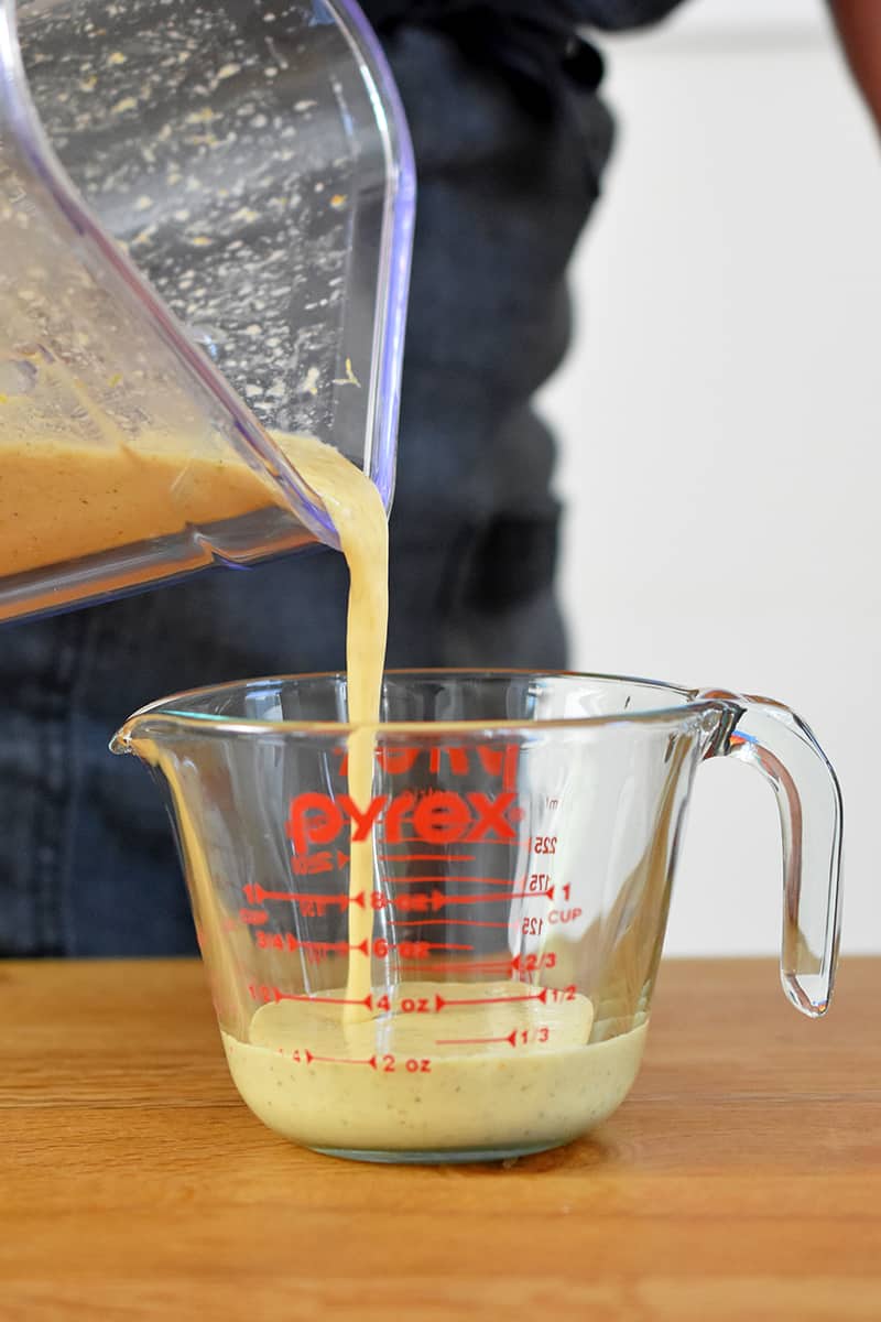 Pouring mojo sauce from a blender into a liquid measuring cup.