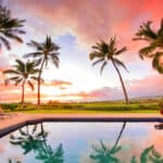 A beautiful Hawaiian sunset with palm trees and a pool. There is text at the top that reads Gluten free on the Big Island.