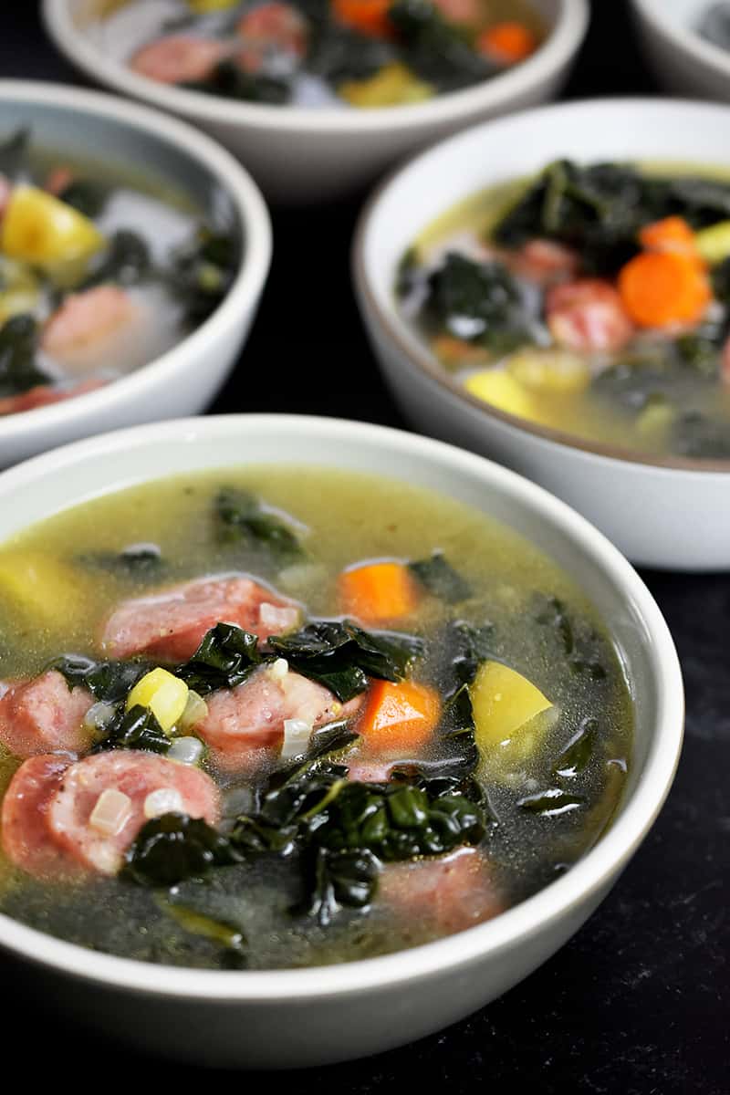 A shot of four bowls filled with sausage and kale soup that can be made in the Instant Pot or on the stovetop.