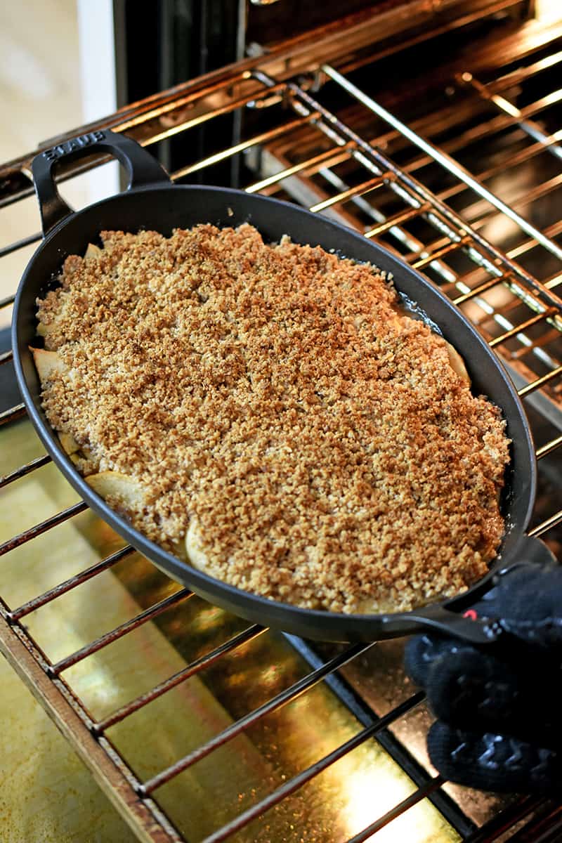An open oven filled with an oval baking dish filled with a golden brown paleo and gluten free apple crisp.