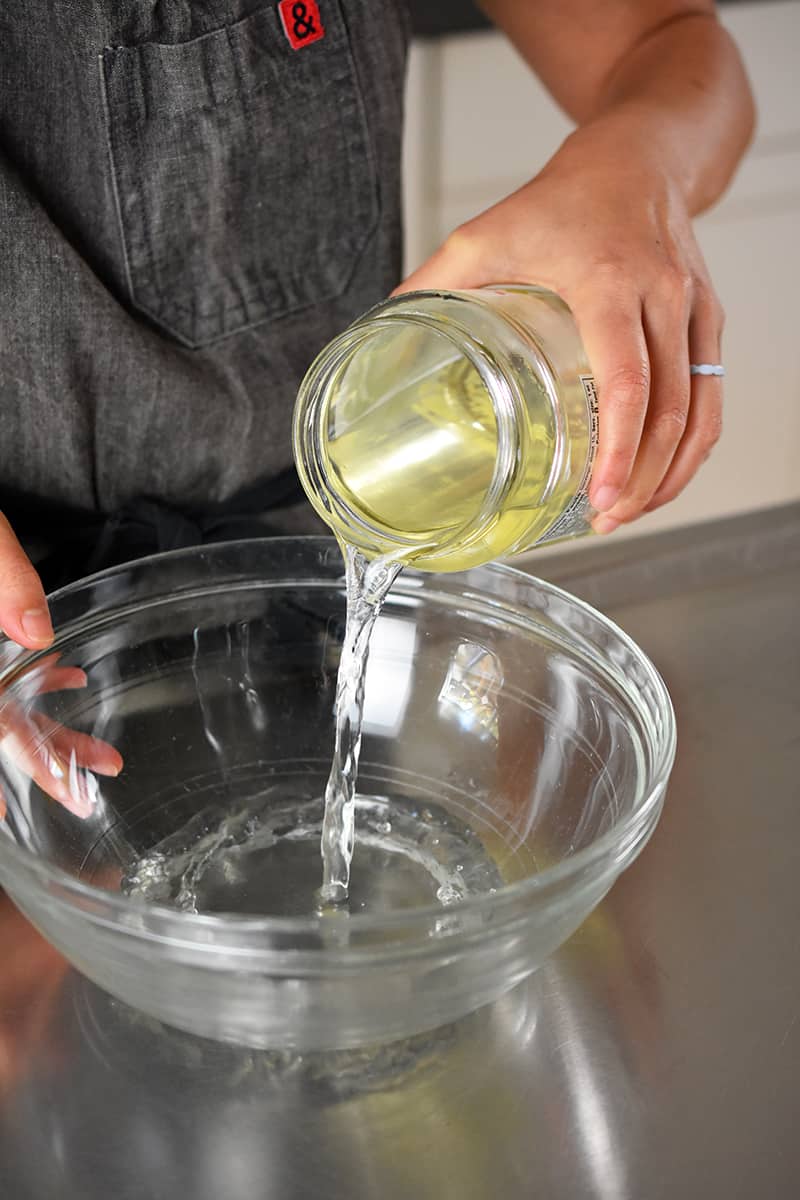 Someone pouring pickle juice into a large bowl.