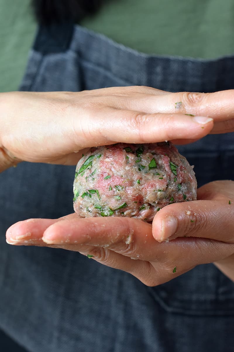 Rolling a meatball in between two hands.
