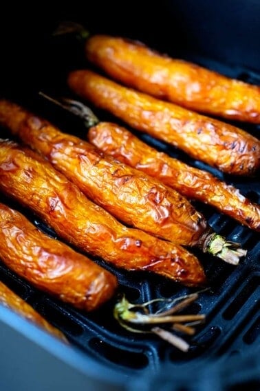 An overhead shot of golden brown carrots in an open air fryer.