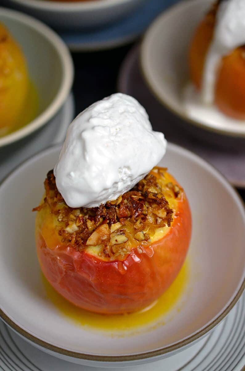 A closeup of a baked apple topped with whipped coconut cream.