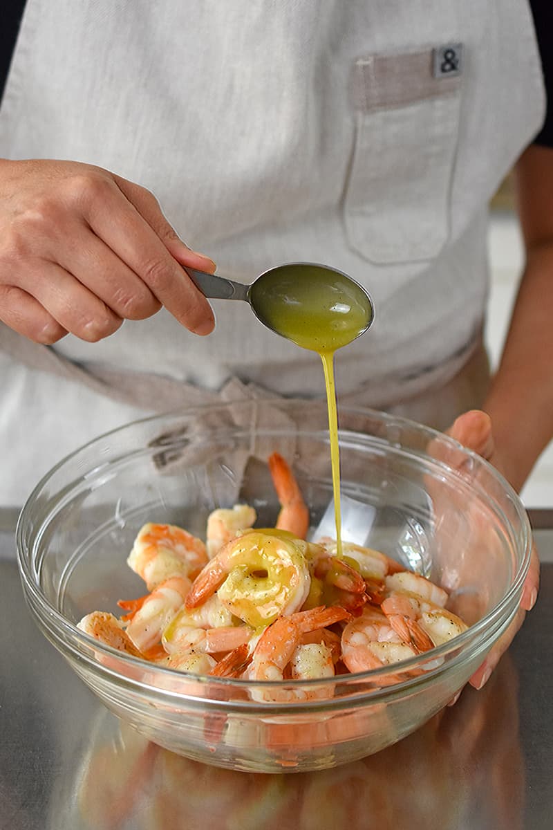 Adding a spoonful of dressing to the shrimp avocado salad.