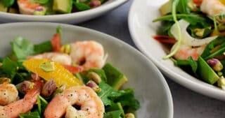 A closeup of four shallow bowls filled with shrimp and avocado salad