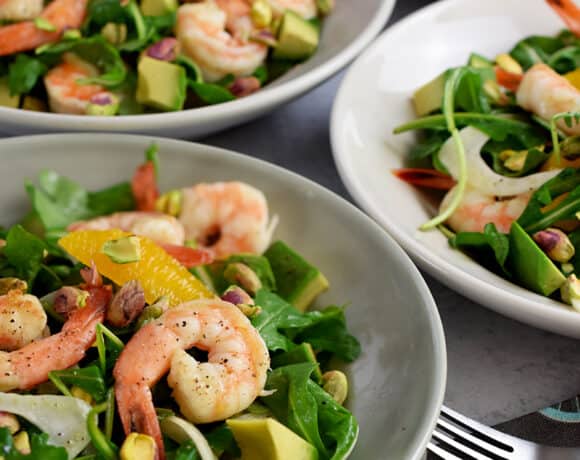 A closeup of four shallow bowls filled with shrimp and avocado salad