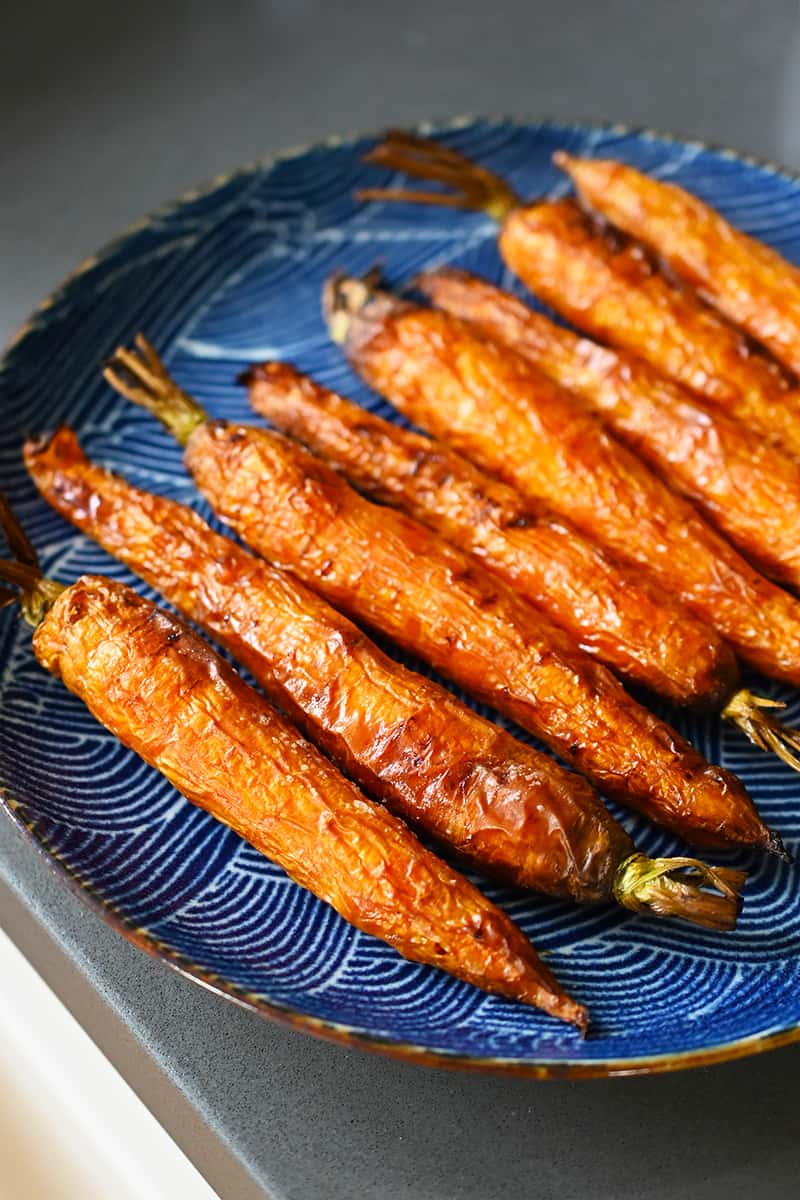 A blue plate topped with air fryer carrots that are golden brown and ready to eat.