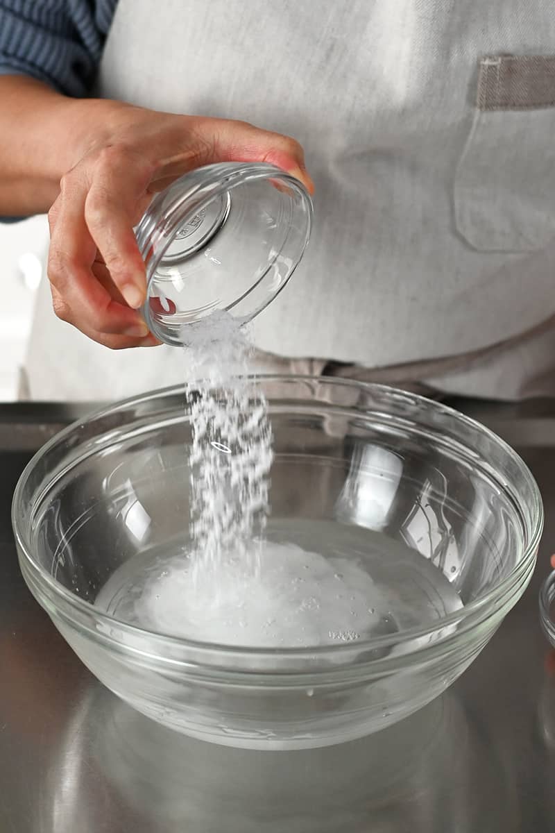 Adding salt to a glass bowl filled with water and baking soda to make an alkaline brine.