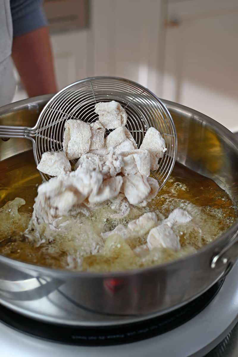 A spider strainer is adding paleo calamari to a large pot of hot oil