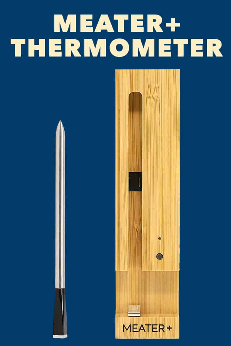 An overhead shot of a Meater Plus thermometer and wooden charging block on a dark blue background.